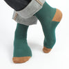 A pair of green mercerised cotton socks with a contrast brown tip, displayed on a model's feet.