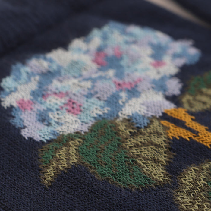 Close-up of a knitted design on fabric with flowers and leaves.