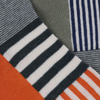 close up of the sock knitted fabric in a colourful geometric pattern, featuring orange, green, and navy stripes