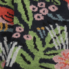 close up of the knitted sock fabric with a jungle-themed pattern including colourful plants, flowers, and animals like leopards and birds on a navy background.