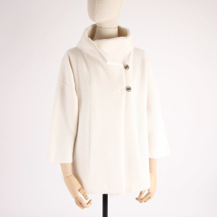 Mannequin wearing a cream-colored textured jacket with a high collar on a white background