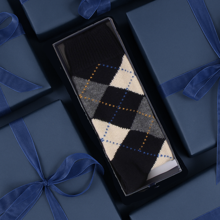 Argyle patterned socks in a box with blue ribbons on a dark background