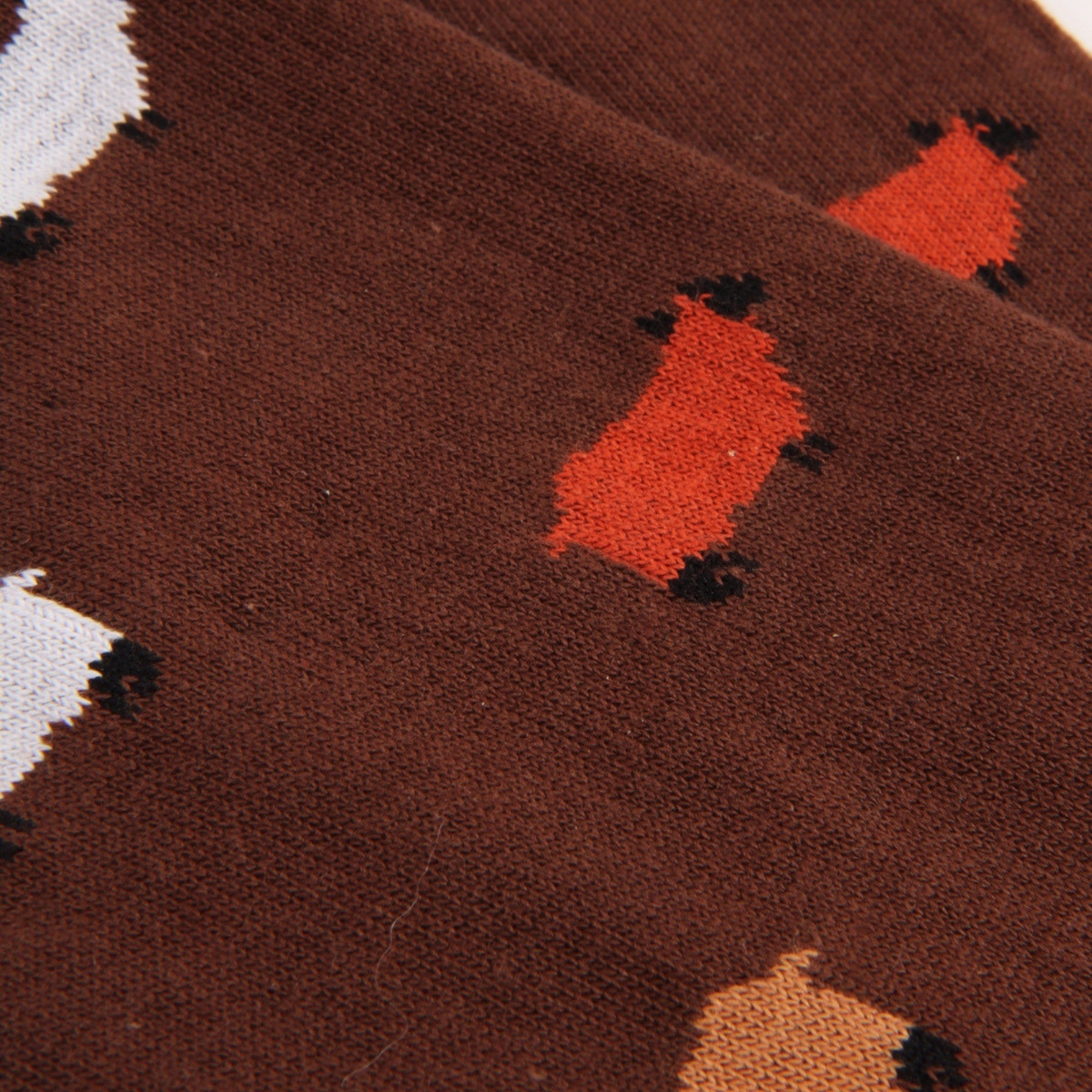 Close-up of a brown knit fabric with a repeating pattern of red, white, and tan foxes outlined in black.
