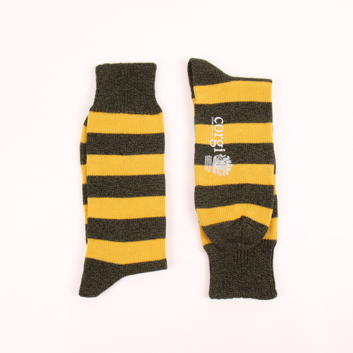 A pair of striped socks laid flat on a white background. The socks feature alternating dark olive green and mustard yellow horizontal stripes, with the brand name 'corgi' and a small crest printed in white on one sock.