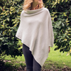A woman standing outdoors wearing a beige textured cashmere poncho with a honeycomb pattern.