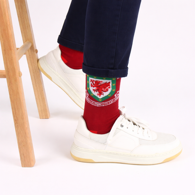 Red socks with a emblem worn by a person in white sneakers on a light background