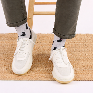 White sneakers worn with Labrador dog patterned socks on a wooden floor.
