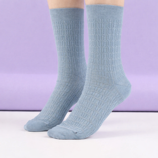 Light blue textured socks on a white surface with a purple background