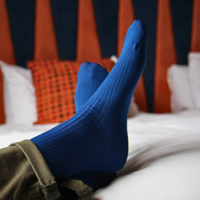 Blue sock on a foot with a striped curtain in the background