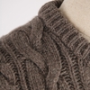 Close-up of a brown knitted sweater on a mannequin against a white background