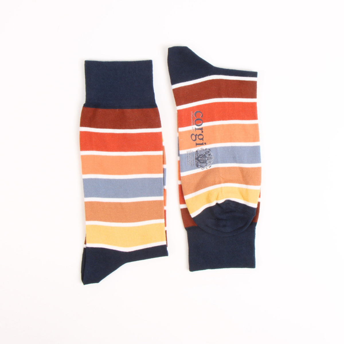 A pair of striped socks laid flat on a white background, featuring horizontal bands of navy, rust red, orange, light blue, yellow, and white, with a vertical brand print reading 'corgi' and a small crest logo.