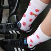Person wearing white socks with red dragons and black trainers in a football stadium.