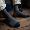 A pair of micro striped cashmere blend socks in a neutral color, worn on a person's legs, showing the mid-calf length and ribbed cuff.