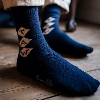 A pair of navy blue cashmere socks with a monogram pattern, showing the socks' texture and the brand name 'Corgi'.