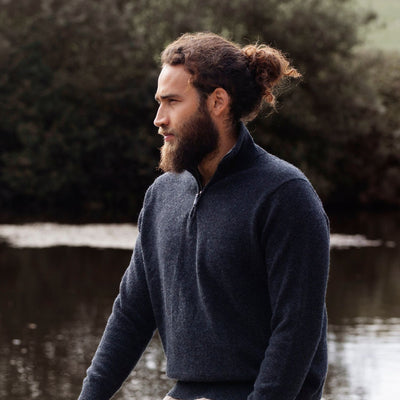 A man wearing a navy blue half zip sweater with a unique contrasting colour collar, standing outdoors.