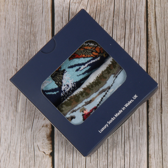 Two pairs of socks with nature and fishing themed designs photographed in a gift box.