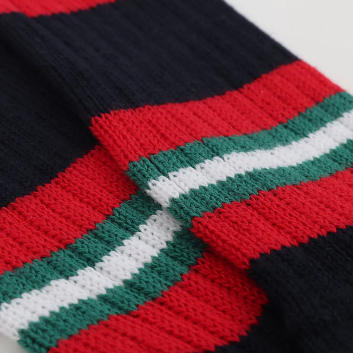 Close-up of a knitted fabric with red, green, and white stripes on a black background.