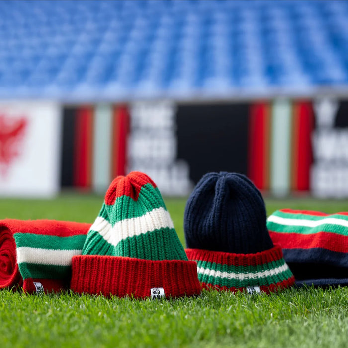 Colorful knitted hats on a grassy field with stadium seats in the background