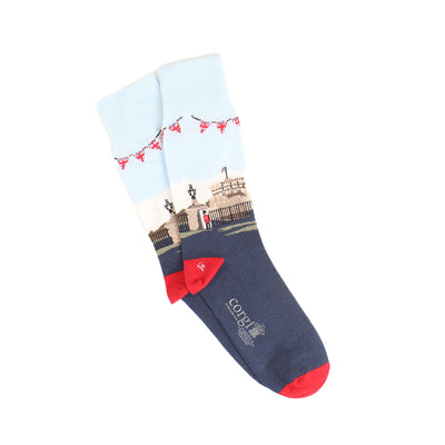 A pair of men's socks with a detailed illustration of Windsor Castle, featuring a predominantly white cuff with a red ribbon design, a blue shaft, and red heel.