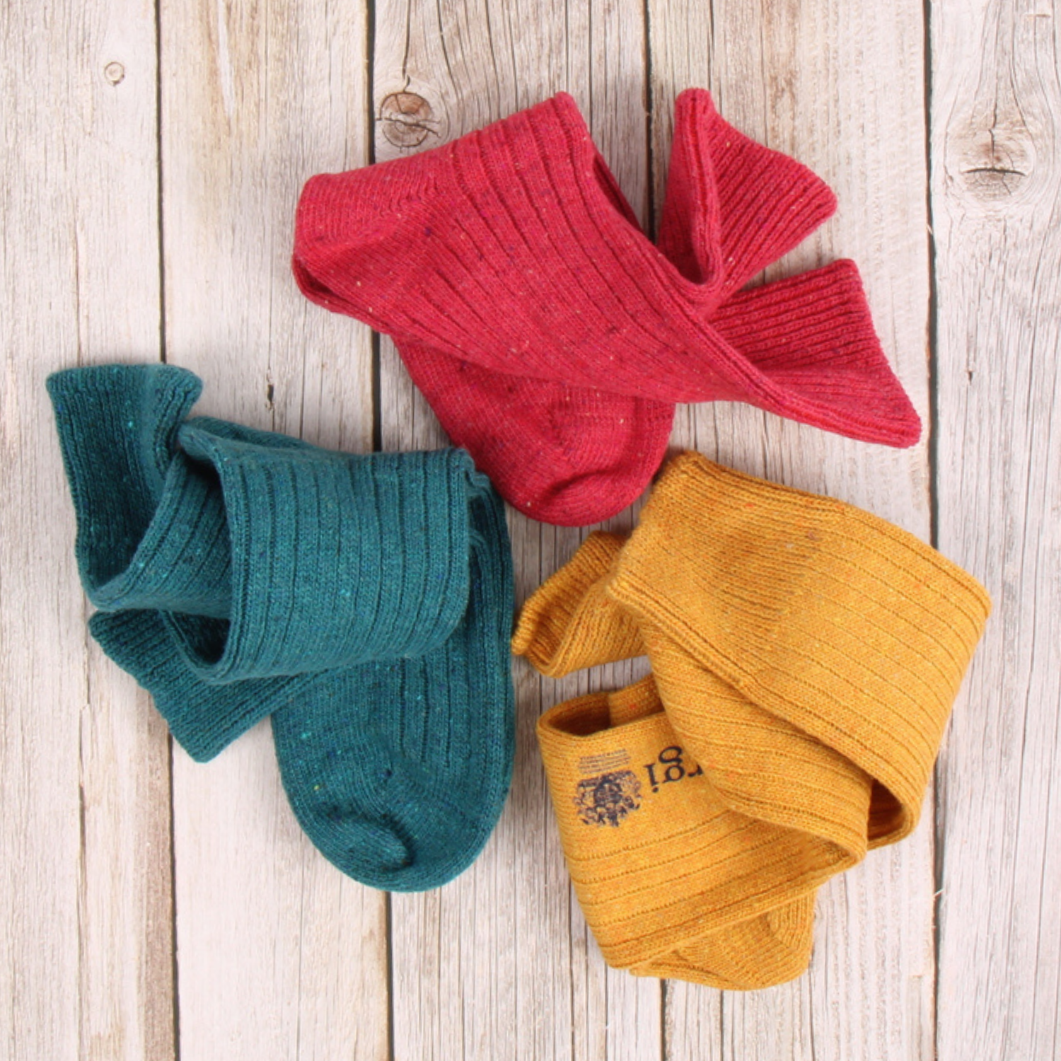 Three pairs of colorful socks (red, teal, mustard) on a wooden surface