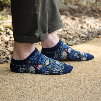 person wearing navy patterned trainer socks on a gravel path

