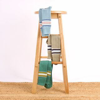 Wooden ladder with colourful socks on a white background