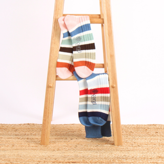 Colorful striped socks on a wooden ladder against a white background