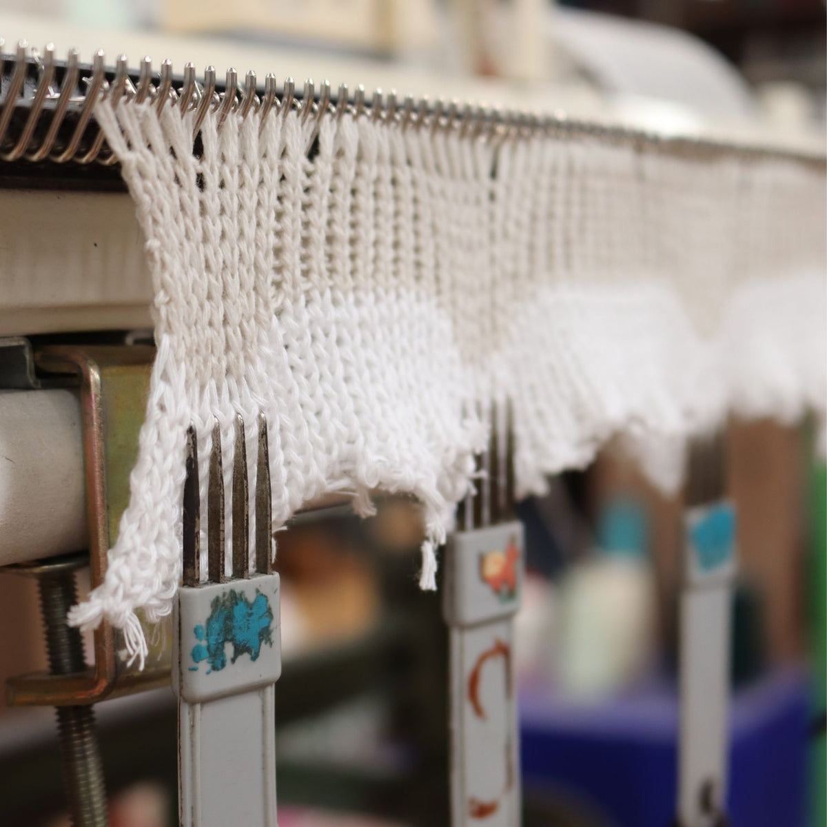 Close-up of a knitting machine with white yarn and blurred background