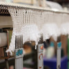Close-up of a knitting machine with white yarn and blurred background