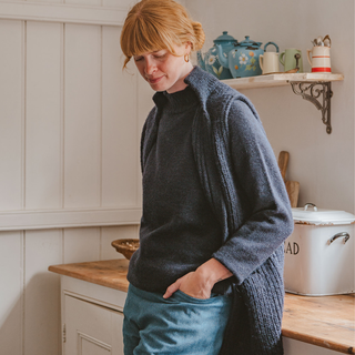 Woman wearing a blue knitted sleeveless cardigan in a kitchen setting