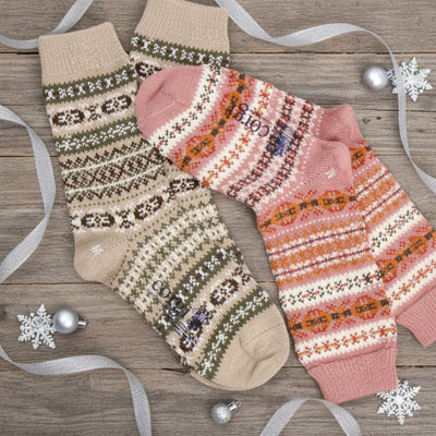 Two pairs of patterned socks, one beige with brown and white designs and the other pink with orange patterns, on a white background.