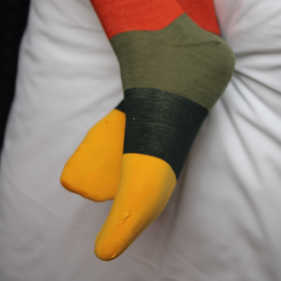 Colourful sock with orange, green, dark green, and yellow stripes on a white background