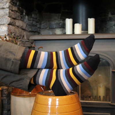 Striped socks being worn, with a fireplace and candles in the background