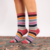 Multicolored striped socks worn by a person on a patterned rug.