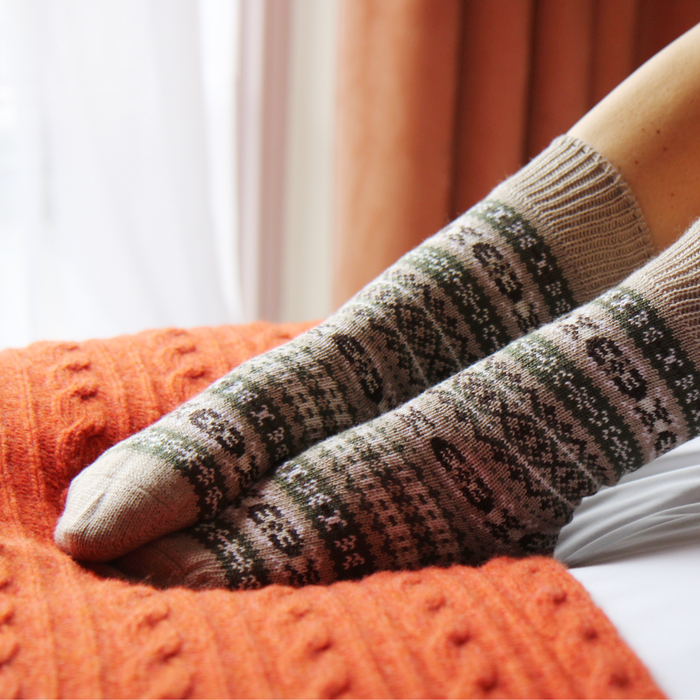 Close-up of feet wearing patterned socks on an orange blanket