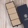 Set of beige socks in an open Corgi box on a wooden surface, with a navy blue box featuring a logo in the background.