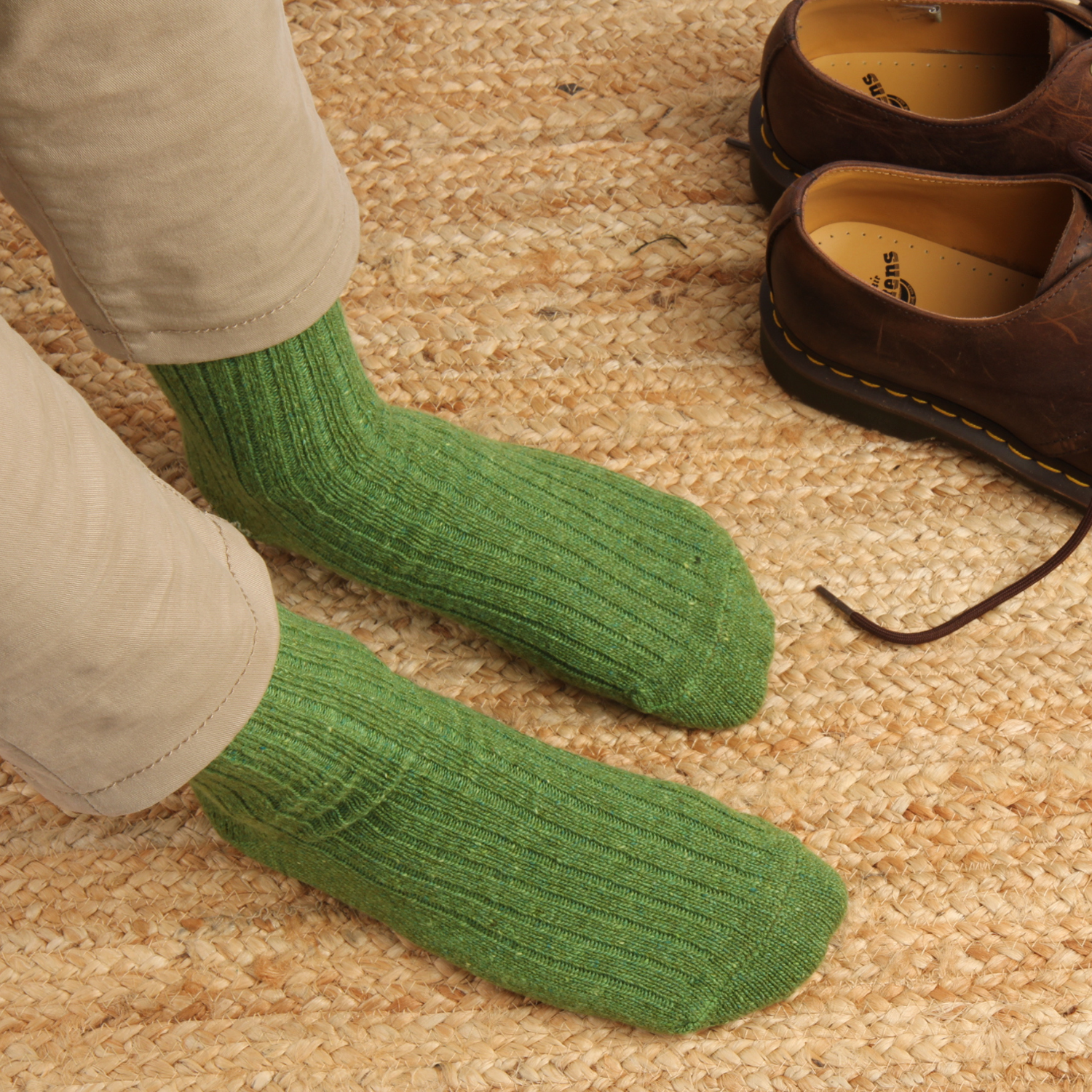 Green socks worn with brown shoes on a carpeted floor