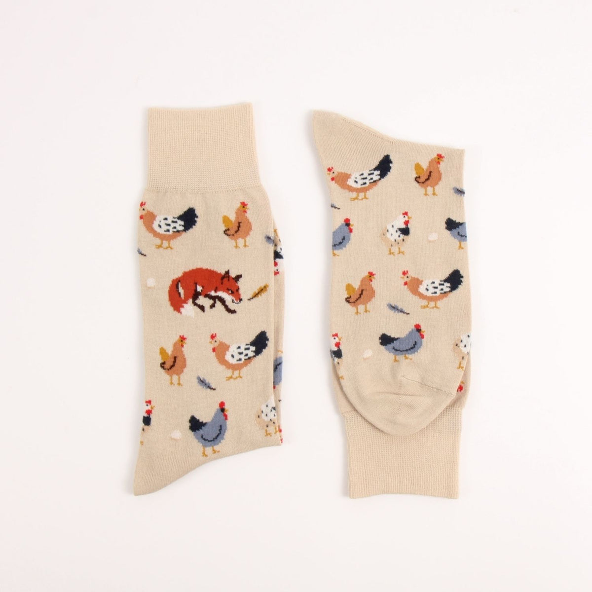 A pair of beige crew socks with a whimsical farm and forest pattern featuring chickens, a fox, and a duck, displayed flat against a white background.