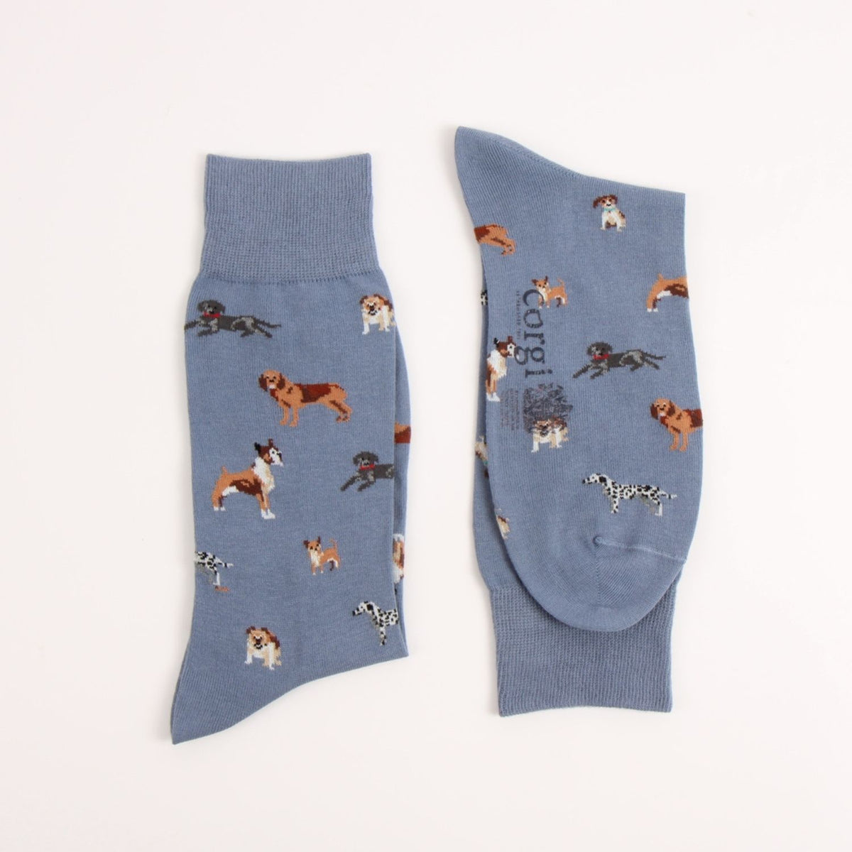 A pair of dusty blue crew socks with an all-over print of various dog breeds, shown flat on a light cream background.