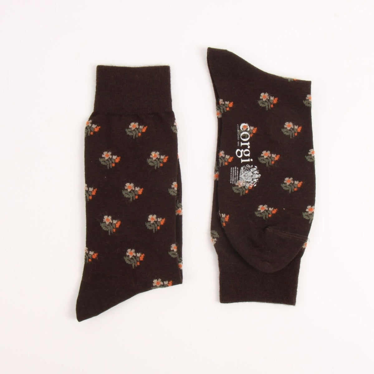 A pair of dark brown crew socks with a small orange and white floral pattern, shown flat on a white background. One sock is shown from the side, and the other shows the top and foot area with the brand name 'corjl' printed vertically in white.