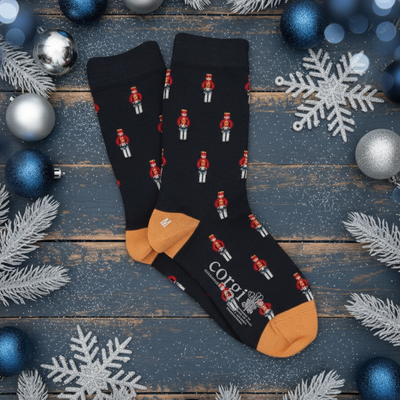 Navy socks with red nutcracker design on a wooden surface with Christmas decorations.