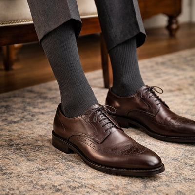Brown dress shoes with charcoal Penarth socks on a patterned rug